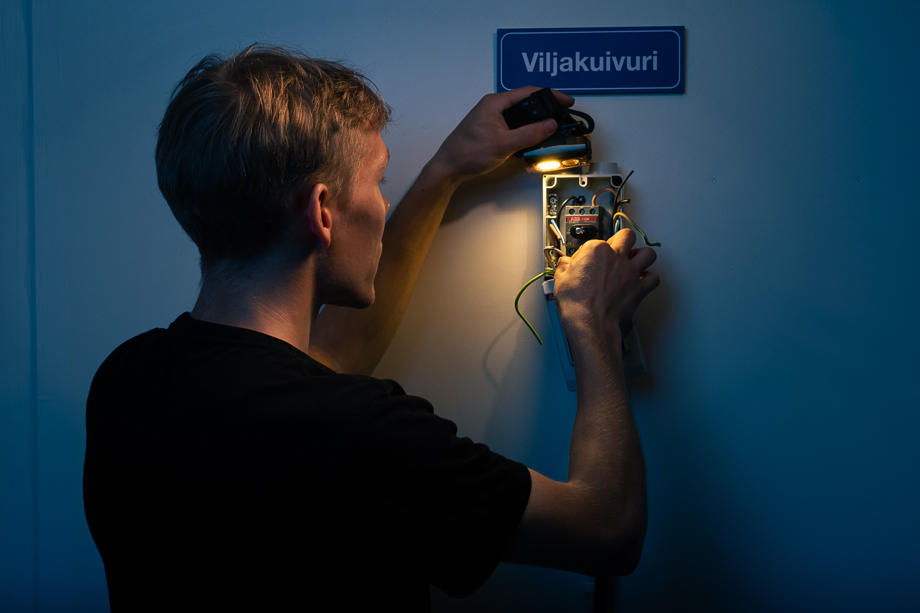 Sähköasentaja asentamassa aurinkopaneelia paikoilleen. Studiokuva